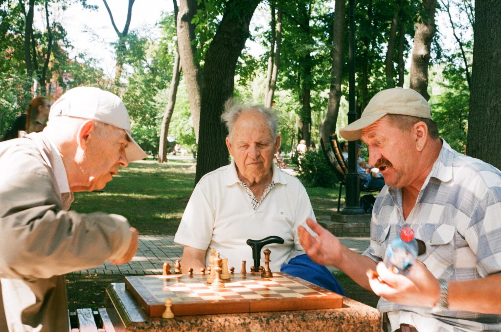 Three elderly men in a park at a chess table