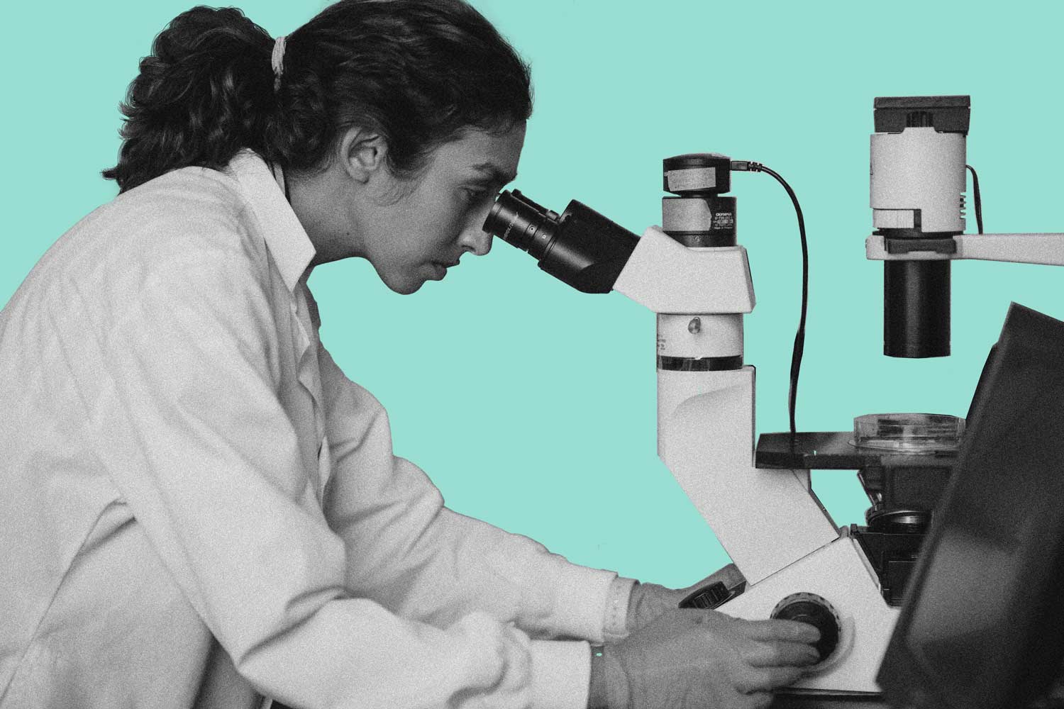 Side view of a researcher looking through a microscope