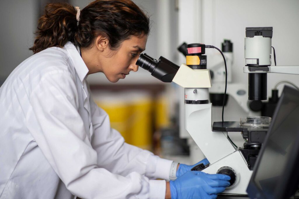 Side view of a researcher looking through a microscope