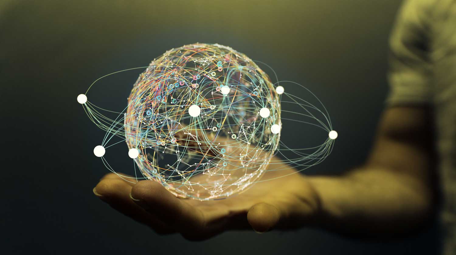 A hand holding a sphere made of points connected by and orbited by network lines