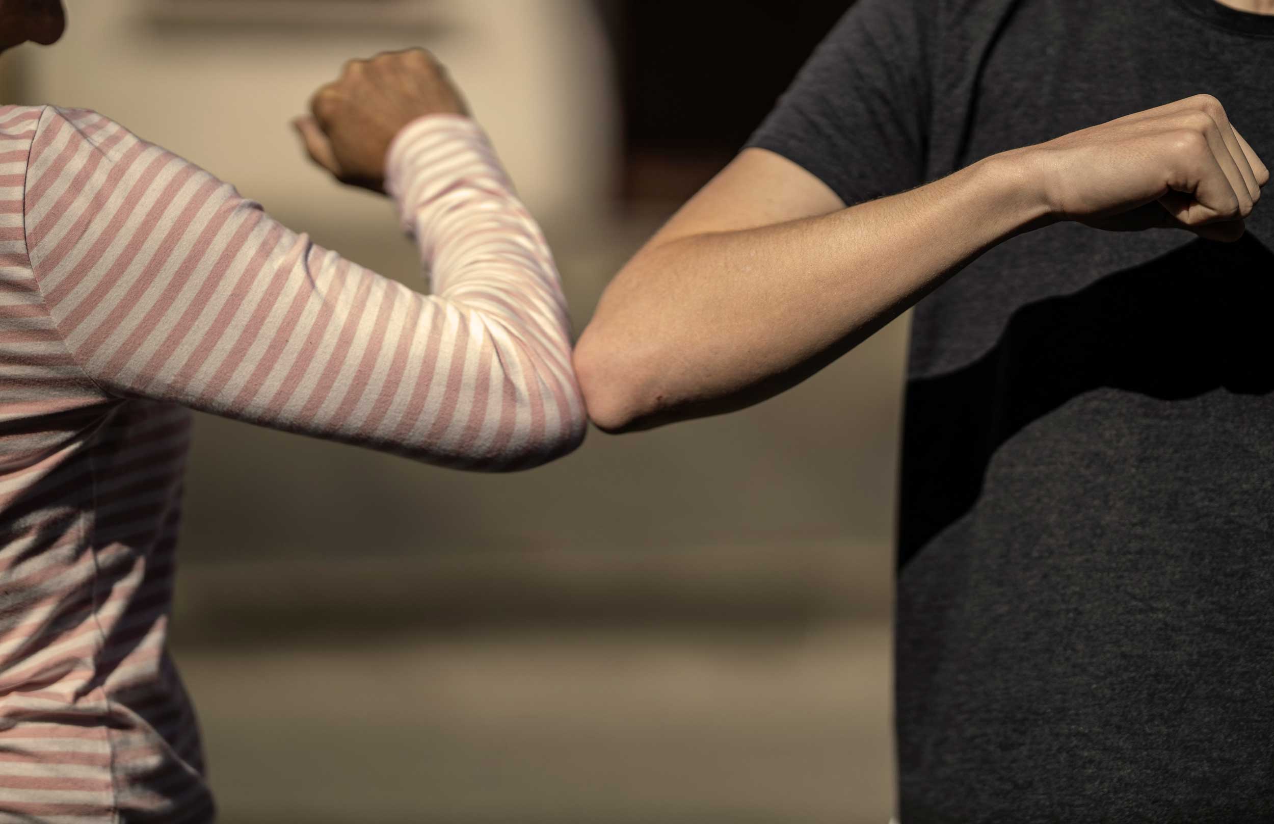 A closeup of two elbows bumping in greeting